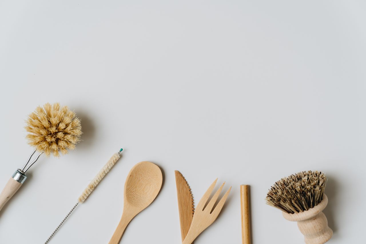 Sustainable wooden kitchen utensils and brushes on a white background, promoting eco-friendly living.